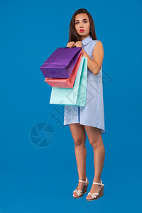 照片来自美丽的年轻女性 在美妙的蓝背景下 带着色彩多彩的购物袋 理发 夏天图片