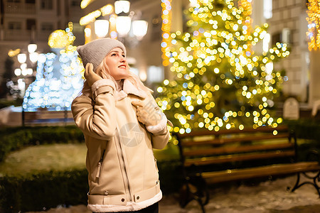穿着时髦的冬衣 编织小白脸帽 围巾的模范圣诞展会 庆祝 晚上背景图片