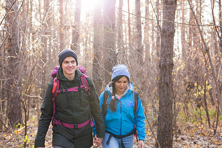 人 登山 冒险 旅游和自然概念   年轻男女用背包在森林中行走图片