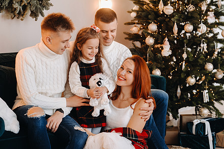 一个幸福的家庭坐在庆祝节日的圣诞树附近的沙发上的近似肖像 快乐的 灯图片