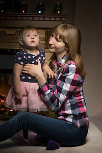 一个年轻的母亲和她的女儿 在壁炉旁边 家图片