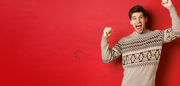 快乐帅哥在圣诞前夜欢欣鼓舞 举起双手 欢呼雀跃 胜利庆祝寒假 站在红色背景上的形象 黑发 圣诞节图片