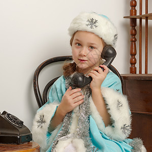 一个穿雪雪少女服装的小女孩 正在谈论旧Pho 帽子 圣诞老人图片