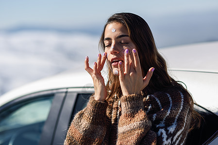 年轻女子在雪地上用防晒霜遮住她的脸 假期 追求图片