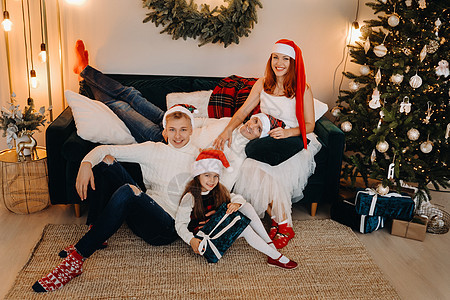 一个幸福的家庭坐在庆祝节日的圣诞树附近的沙发上的近似肖像 爸爸 庆典图片