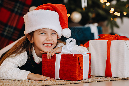 一个快乐的小女孩 戴着圣诞老人帽子 带着礼物笑着微笑 脸 十二月图片