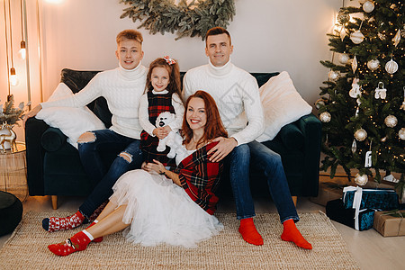 一个幸福的家庭坐在庆祝节日的圣诞树附近的沙发上的近似肖像 父母 冬天图片
