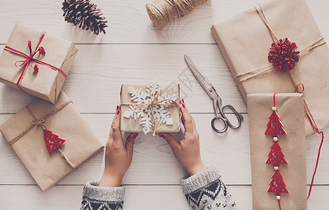 妇女用手把圣诞节假期礼物和工艺绳子包装在一起 面目全非 快乐的图片