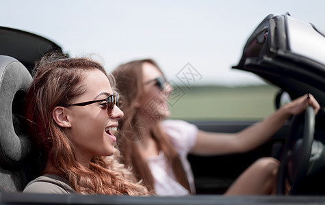 两个时髦的女孩乘坐敞篷车旅行 路 伸出 假期图片