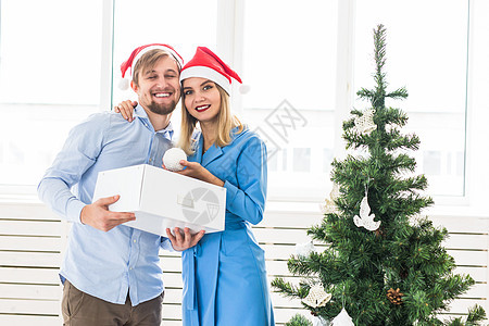 节假日和节日概念   年轻家庭夫妇装饰圣诞树 浪漫的 爱图片