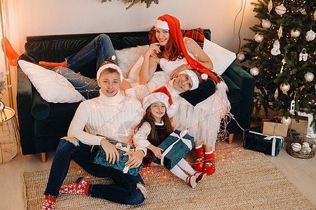 一个幸福的家庭坐在庆祝节日的圣诞树附近的沙发上的近似肖像 微笑 闪光图片