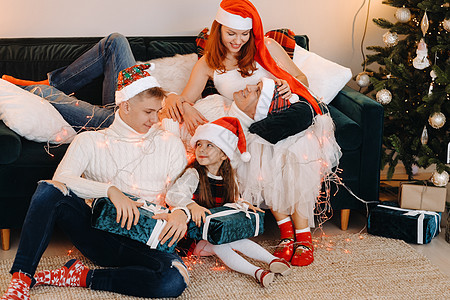 一个幸福的家庭坐在庆祝节日的圣诞树附近的沙发上的近似肖像 坐着 男人图片