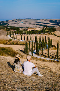 情侣在意大利托斯卡纳度假 观看意大利欧洲托斯卡纳的金色山丘 托斯卡纳景观与谷物田 柏树和日落时山上的房屋 欧洲托斯卡纳的夏季乡村图片