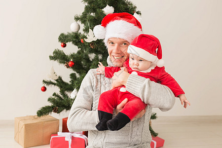 父亲带着他的男婴戴着圣诞老人的帽子庆祝圣诞节 男人 父母图片