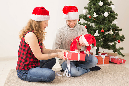 妈妈儿子快乐的一对夫妇与婴儿 一起庆祝圣诞节在家里 盒子 夫妻背景