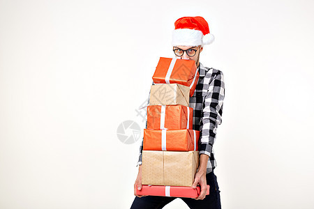 假期和礼物的概念 — 戴着圣诞老人帽的风趣男人拿着许多白色背景的礼盒 喜庆 十二月图片