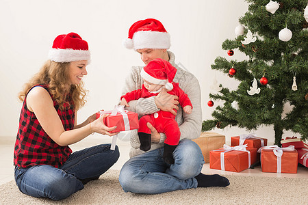 快乐的一对夫妇与婴儿 一起庆祝圣诞节在家里 盒子 女儿图片