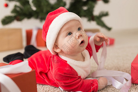 漂亮的小宝宝庆祝圣诞节 新年假期 穿着圣诞服装 戴着圣诞帽和礼盒的婴儿 帽子 幸福图片