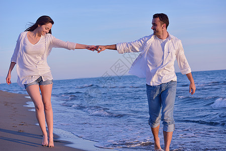 沙滩上的年轻情侣玩得开心 手 天空 美丽的 海洋图片