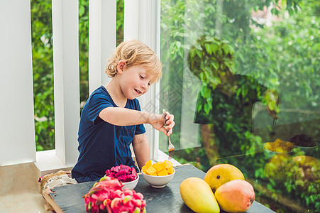 小可爱男孩在阳台上吃芒果 异国情调 温泉 男生 微笑图片