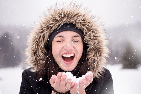 年轻女子在雪天吹雪 漂亮的 女性 帽子 乐趣 户外图片