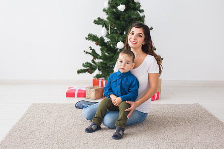 圣诞节 单身父母和假期概念 — 可爱的小男孩在家里为他的母亲拿着圣诞礼物 父亲 圣诞帽图片