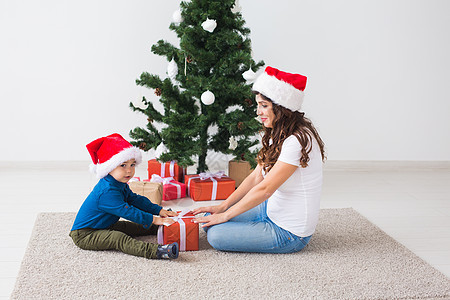 圣诞节 单身父母和假期概念 — 可爱的小男孩在家里为他的母亲拿着圣诞礼物 女士 男生图片