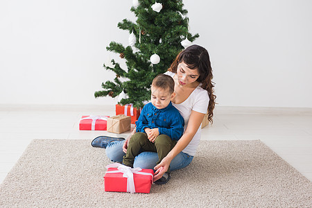 圣诞节 单身父母和假期概念 — 可爱的小男孩在家里为他的母亲拿着圣诞礼物 微笑图片