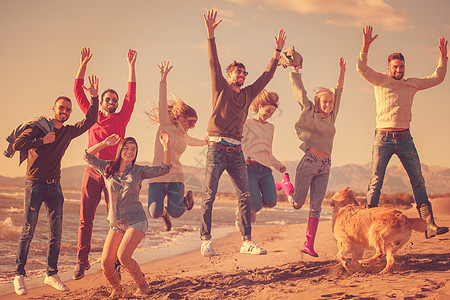 年轻朋友在秋天海滩一起跳跃 自由 人民 太阳 快乐图片