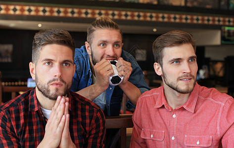 三名穿便衣的男人为橄榄球欢呼 坐在酒吧柜台时却拿着啤酒瓶子喝着 乐趣 足球图片