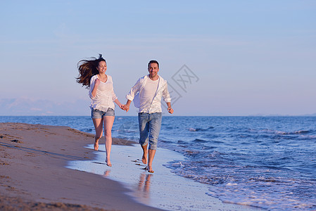 沙滩上的年轻情侣玩得开心 户外 跳 手 生活图片