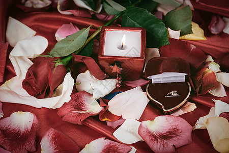 玫瑰花瓣背景上的钻石戒指和蜡烛 假期 庆典 爱图片