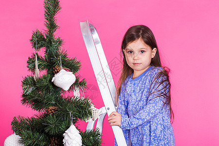 圣诞节和节日概念-一个小女孩在粉红背景上装饰圣诞树的粉红色背景 长的 健康图片