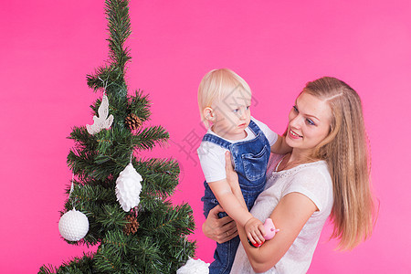 假期 家庭和圣诞节概念 — 年轻妈妈和她的小女儿在粉红色背景的圣诞树旁 新年 美丽的图片