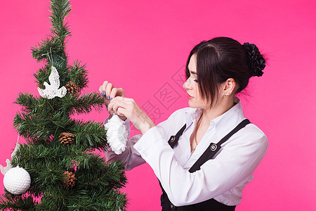 人 假期和圣诞节概念 — 粉红色背景中装饰圣诞树的女人 季节 庆典图片