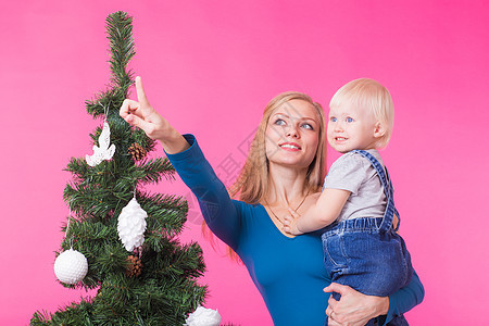 圣诞节 假期和人的概念 — 年轻快乐的女人带着女儿在圣诞树上展示装饰品 新年 妈妈图片