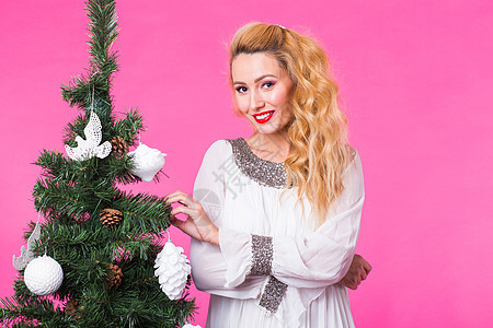 假日概念   在粉红背景的圣诞节树附近的金发妇女 金发女郎 快乐图片