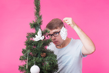 圣诞节 假期和人的概念 — 年轻快乐的男人在粉红色背景的圣诞树上展示圣诞装饰 圣诞节快乐 围巾图片