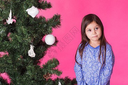 儿童 假期和圣诞节概念 — 粉红色背景中靠近圣诞树的小女孩 可爱的 幸福图片
