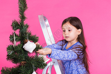 儿童 假期和圣诞节概念 — 粉红色背景中装饰圣诞树的小女孩 闲暇图片