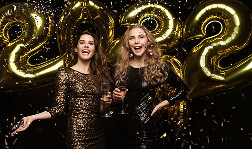 两位年轻女士喝香槟 女孩们的画面是 带着气球在黑人背景中被孤立 在圣诞节或新年2022年夜派对上玩得开心 笑 夫妻图片