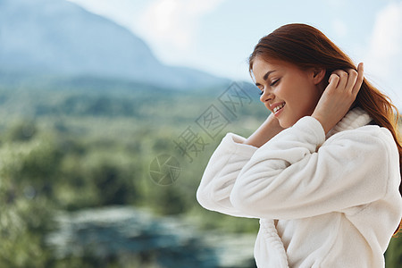 美丽的美女白袍仰慕窗外未变的风景 喝 温泉图片