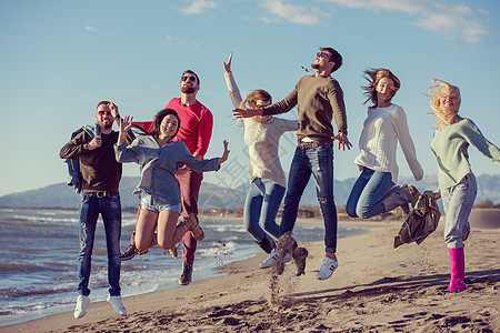 年轻朋友在秋天海滩一起跳跃 幸福 美丽的 乐趣 假期图片