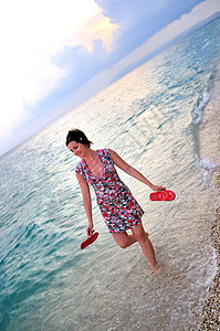 快乐和美丽的女人独自一人在海滩上行走图片