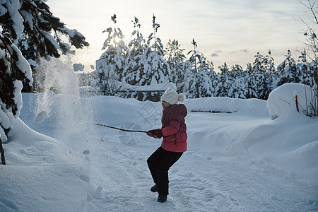 女孩在美丽的阳光明媚的冬季日落下清雪 降雪图片