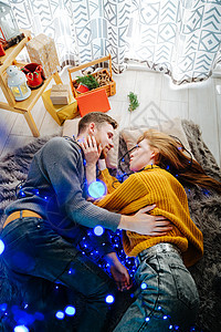 相爱的情侣躺在地上 灰色软毯子上有蓝色灯光 圣诞节装饰 快乐的图片