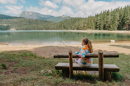 高山湖泊岸边的年轻女孩 山湖背景下的女孩背影 坐在黑山美丽的黑湖附近的年轻女孩 夏日清晨的原创壁纸 云 太阳图片