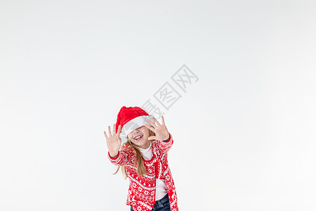快乐的女孩跳舞的画像 穿着红色圣诞毛衣和孤立在白色背景上的圣诞老人帽子 穿着圣诞马鹿毛衣的年轻白种人快乐微笑的金发女孩很开心 情图片