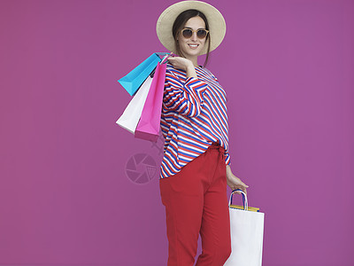 携带粉红背景购物袋的年轻妇女 太阳镜 时尚 奢华图片