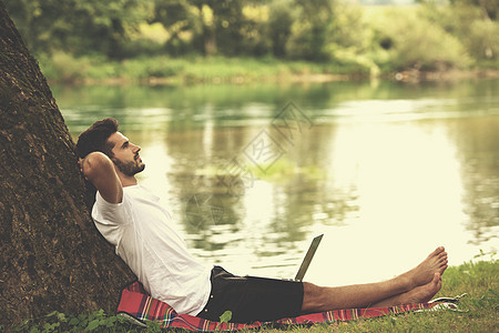 在河岸上使用笔记本电脑的男子 网络 假期 技术图片